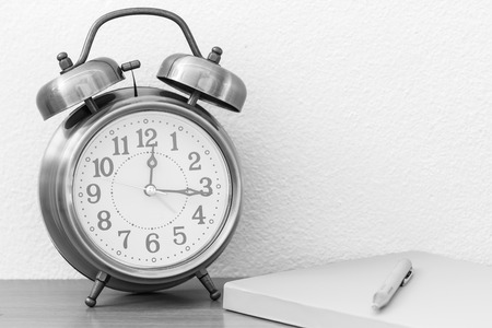 Retro alarm clock with pen and yellow notebook backgroundの写真素材