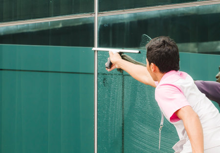 Worker cleaning windows in buildingの写真素材