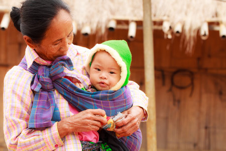 THAILAND-DECEMBER 17, 2014: Unidentified mother Lahu tribe is proudly presenting his baby in the village of bann Jabusi, Chiang Rai province, Thailand.のeditorial素材