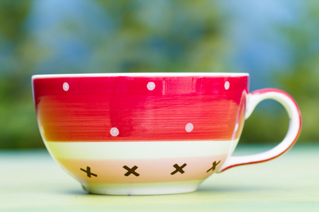 Close-up of red coffee cup with tree leaf backgroundの写真素材