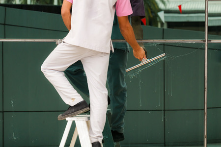 Worker cleaning windows in buildingの写真素材
