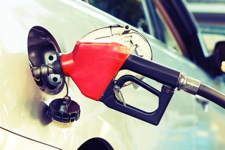 Red pumping fuel oil in car at gas station, retroの写真素材