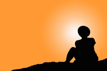Woman silhouette sitting alone on rock watching orange sky and sunの写真素材