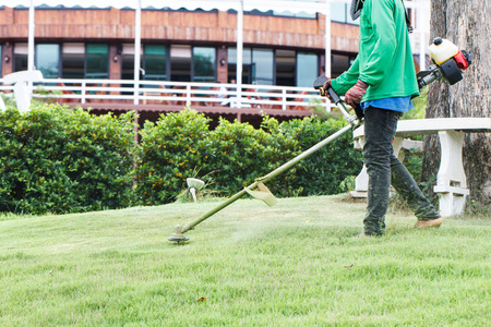Worker cutting grass with lawn mowerの写真素材