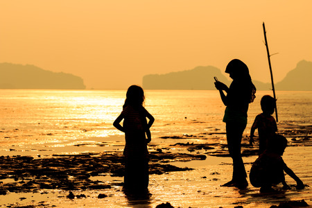 Silhouette mother take photo her children on beach, Thailandの写真素材