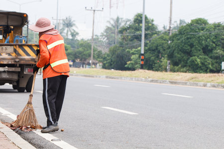 SATUN, THAILAND-AUGUST 27 2015: Blue  trash bin with  worker cleaning the road background. Photo from local road Satun, Thailandのeditorial素材