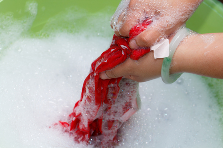 Hand washing clothes in the green bowlの写真素材