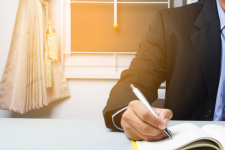 Business suited man writing schedule dairy book at home