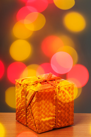 Golden chrismas box with red and yellow bokeh backgroundの写真素材