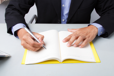 Business man writing with pen at the deskの写真素材