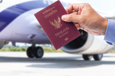 Hand with Thailand passport with airplane backgroundの写真素材
