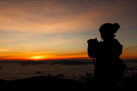 Silhouette of tourist on Phu Chi Fa Forest Park take pictures with digital camera at sunrise time - Chaingrai, Thailandの写真素材