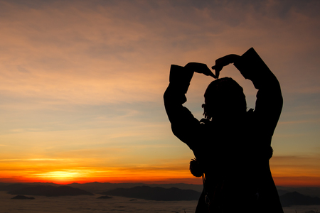 silhouette of woman gesturing success  over morning skyの写真素材