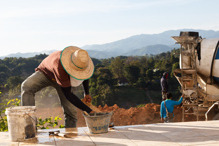 Construction workers making floor with mountain backgroundの写真素材