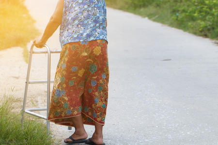Elderly disability woman walking with walker on urban streetの写真素材