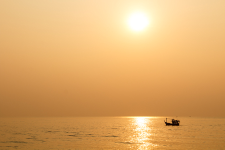 Minimalist of silhouette small boat in ocean when sunsetの写真素材