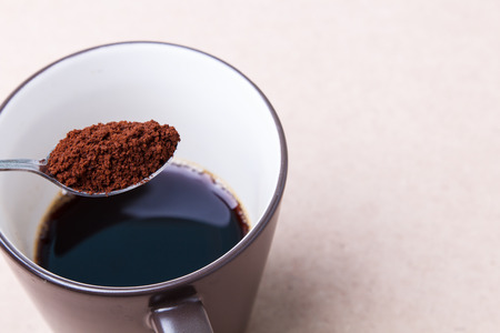 Spoon of black coffee in to brown cupの写真素材