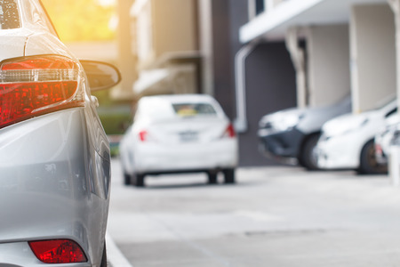 Silver car parking in lot outdoor with car running backgroundの写真素材