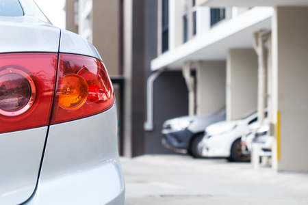 Silver car parking in lot outdoor with car running backgroundの写真素材