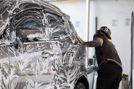 Worker washing car at the car wash shop to clean up dirt and keep the health of the driver and passengersの写真素材