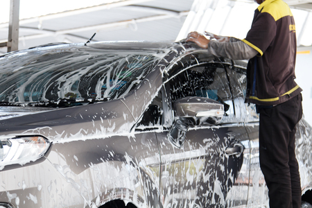 Worker washing car at the car wash shop to clean up dirt and keep the health of the driver and passengersの写真素材