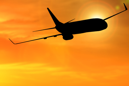 Silhouette of airplane flight flying with sunset and orange sky backgroundの写真素材