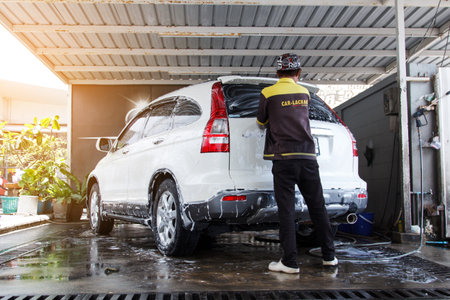 BANGKOK, THAILAND-AUGUST 14, 2017: The rear view photo of the car washing in the car wash shop with the cleaning staff in the back on August 14, 2017 in Bangkok, Thailandのeditorial素材