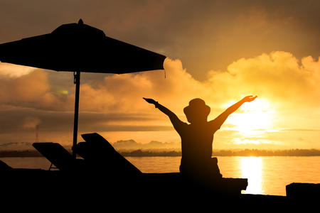 Silhouette of woman relaxing on beach chairs and umbrellas at the seaside, perfect for a holiday getaway.の写真素材