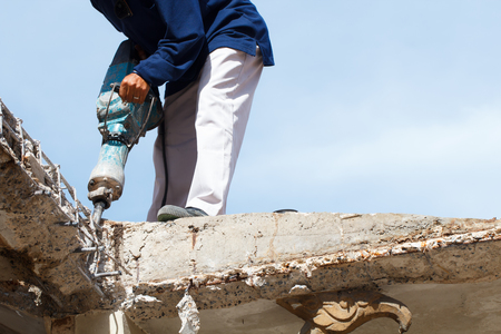 Construction worker repairing the roof with electric drill at the construction siteの写真素材