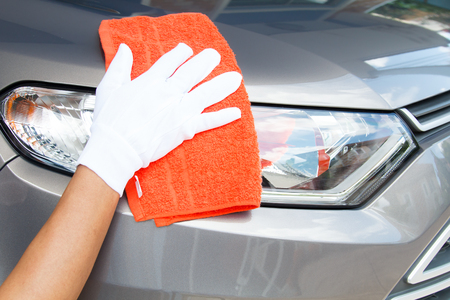 Hand of employees worker use clean orange cloth with white glove to wipe the car after washing in the car wash shopの写真素材