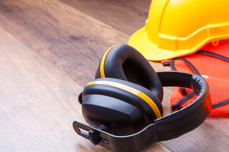Ear protection hard had construction and reflective shirt placed on the wooden floor represents the concept of keeping the quality of hearingの写真素材