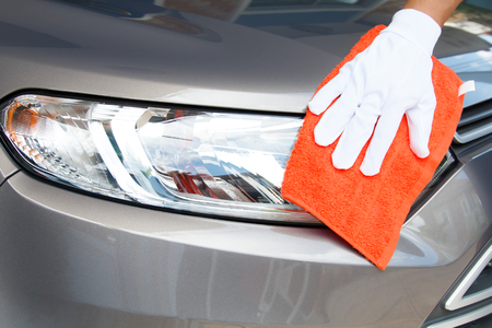 Hand of employees worker use clean orange cloth with white glove to wipe the car after washing in the car wash shopの写真素材