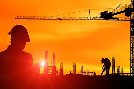 Silhouette construction engineer in the process of checking the construction site for the early morning jobs with lens flare light effectの写真素材