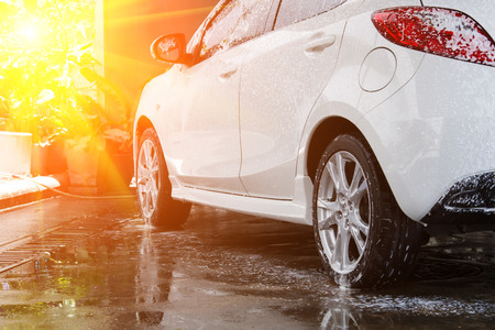 White car washing at the car wash shop to clean up dirt and keep the health of the driver and passengers with lens flare effectの写真素材