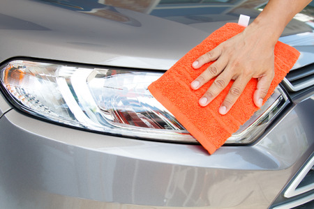 Hand of employees worker use clean orange cloth to wipe the car after washing in the car wash shopの写真素材