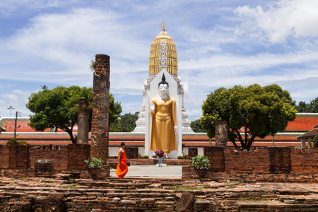 PHITSANULOK, THAILAND-SEPTEMBER 3, 2017: Buddhist worshiping the statues of the great Buddha while the monk pass in daytime on September 3, 2017 in Phitsanulok, Thailandのeditorial素材