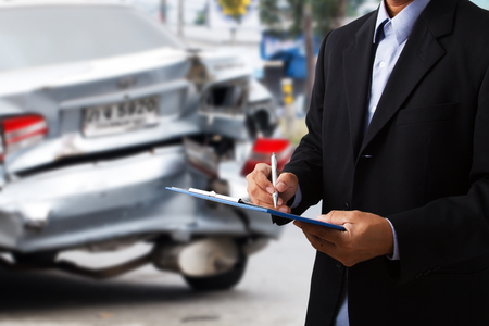 Car insurance agents writing clipboard as a proof of insurance claim for car accident damaged の写真素材