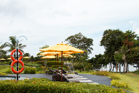 Outdoor beach chairs and yellow umbrellas for holiday vacations in the gardentの写真素材