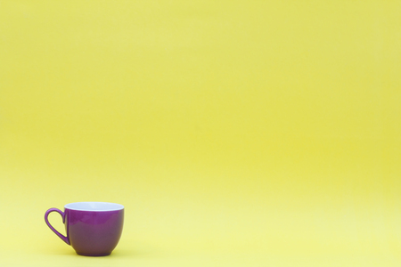 Minimalist image of a purple coffee mug on a yellow background.の写真素材