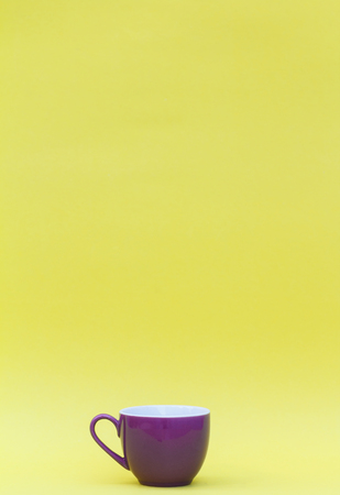 Minimalist image of a purple coffee mug on a yellow background.の写真素材
