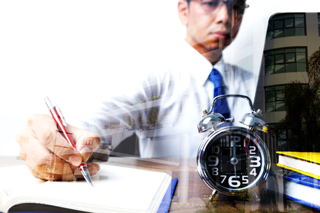 Double exposure of businessman working up to midnight with building, concept of busy and hard workの写真素材