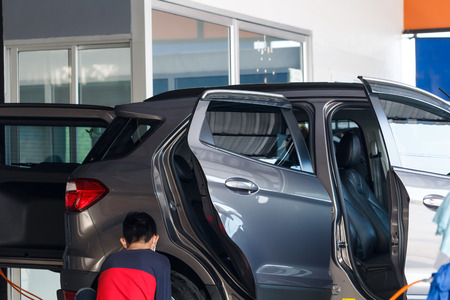 Worker washing car at the car wash shop to clean up dirt and keep the health of the driver and passengersの写真素材