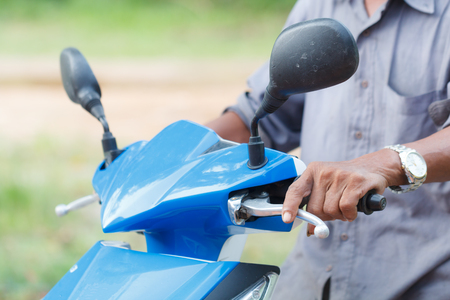 Hand of rural man driving motorcycle, reflecting the rural lifestyle of Thailandの写真素材