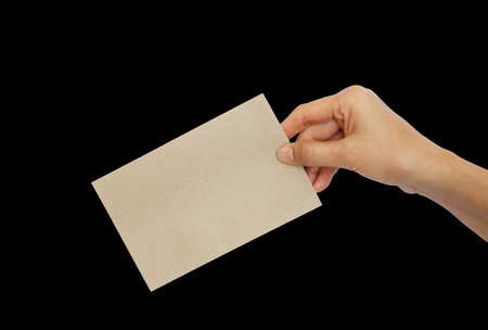 Woman hand holding brown envelope isolated on black backgroundの写真素材