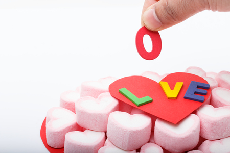 Hand put o letter with pink marshmallow in heart shape, Macro shot of sweet candy heart for love theme on Valentine conceptの写真素材