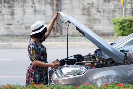 Asian woman waiting insurance company to see the car for repair the sideの写真素材