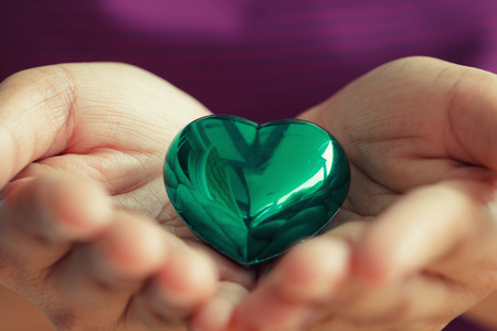 Green heart shape in woman hand, Macro shot of love theme on Valentine conceptの写真素材