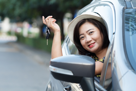 Happy woman with hat and key in car on relaxing tripの写真素材
