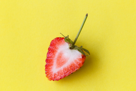 Half strawberry on yellow background with pastel colorの写真素材