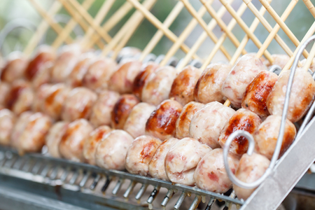 Thai street food, Sausage is grilled on a hot plate to prepare customersの写真素材